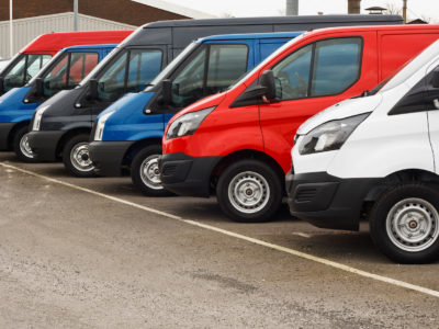 row of different marques of commercial vehicles or vans for retail sale on a motor dealers lot all logos removed